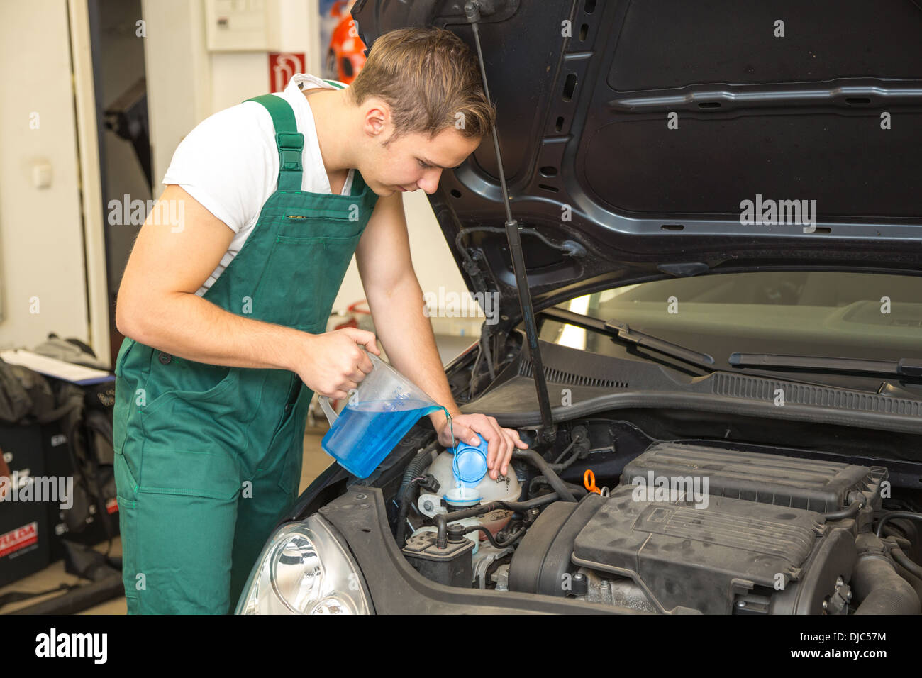 Mechanic ricariche di liquido di raffreddamento o liquido di raffreddamento nel motore di una automobile Foto Stock