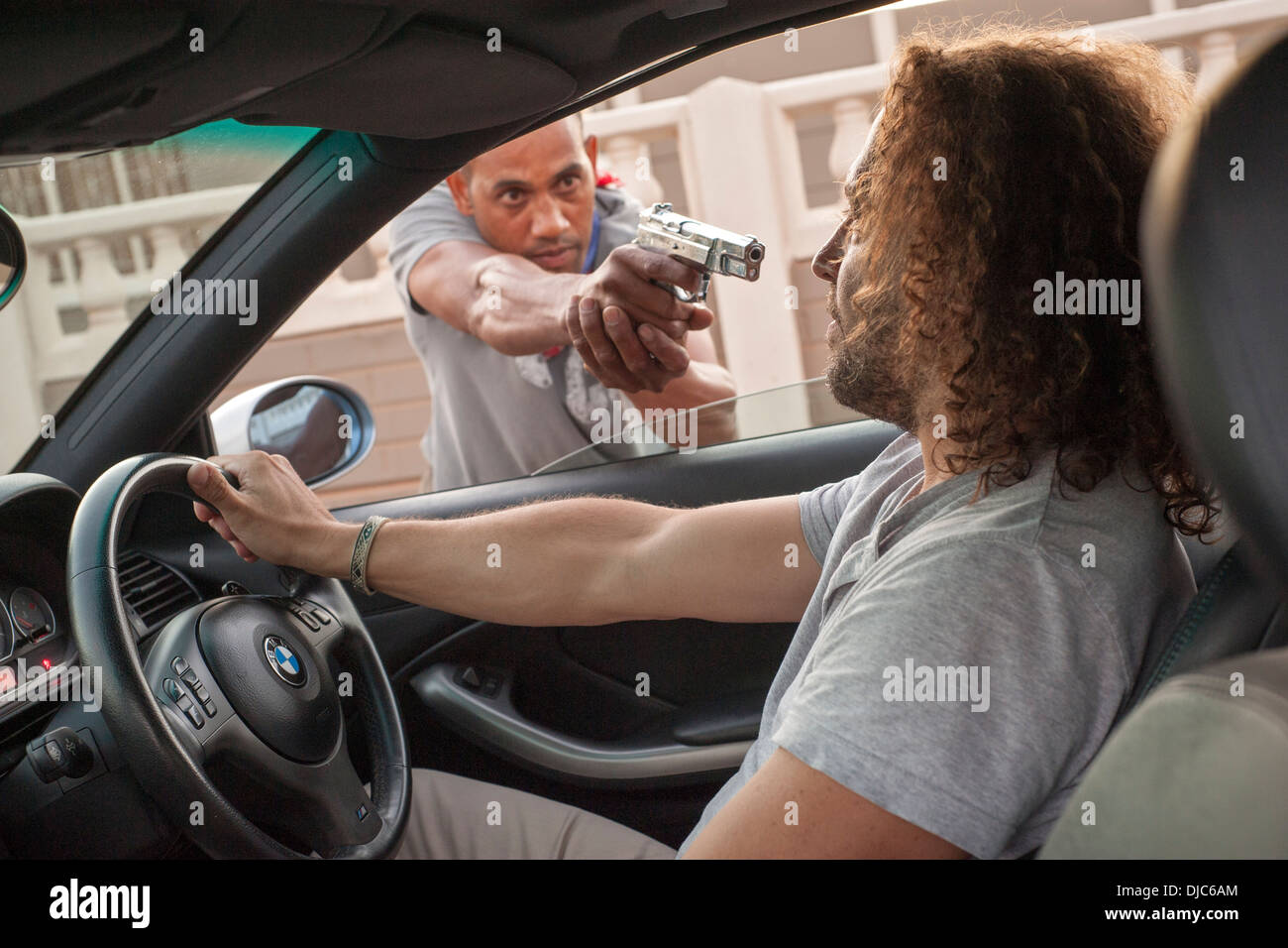 L'uomo getting carjacked a gunpoint. Foto Stock