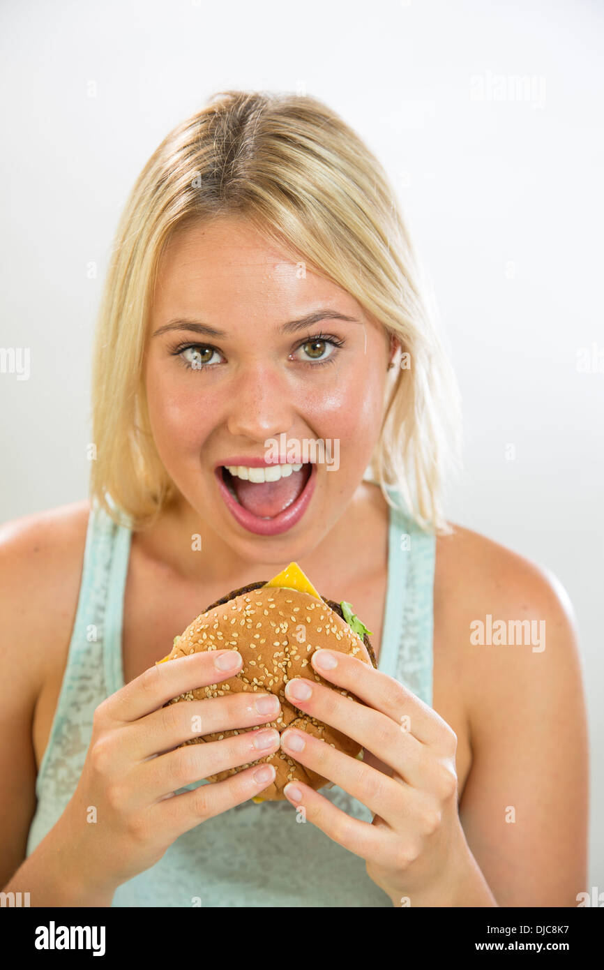 Giovane donna di mangiare hamburger Foto Stock