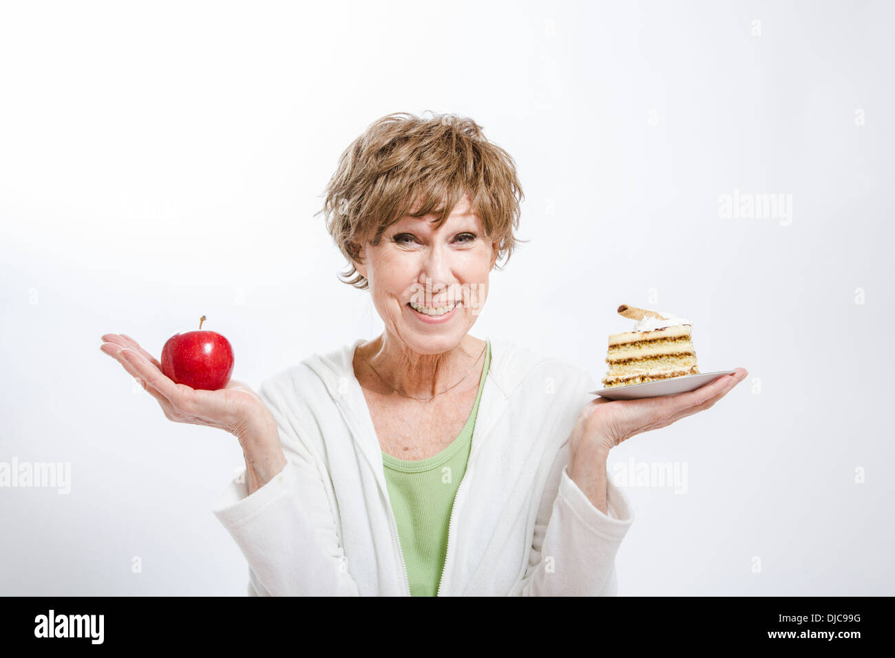 Donna matura tenendo un apple e il pezzo di torta Foto Stock