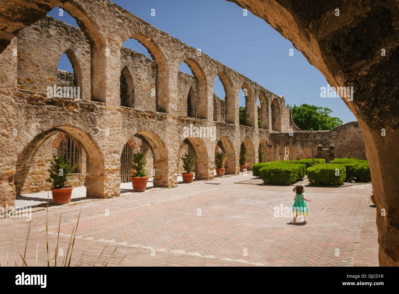 Bambina che corre attraverso il cortile centrale colonnato e presso la missione di San Jose. San Antonio, Texas. Foto Stock