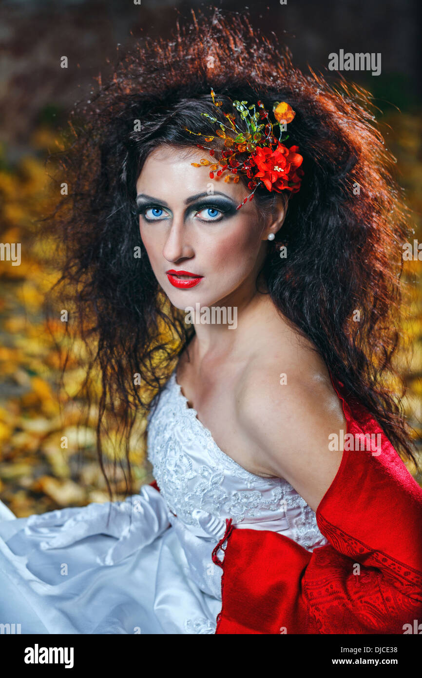 Sposa attraente in un abito da sposa con brillante trucco, scialle rosso Foto Stock