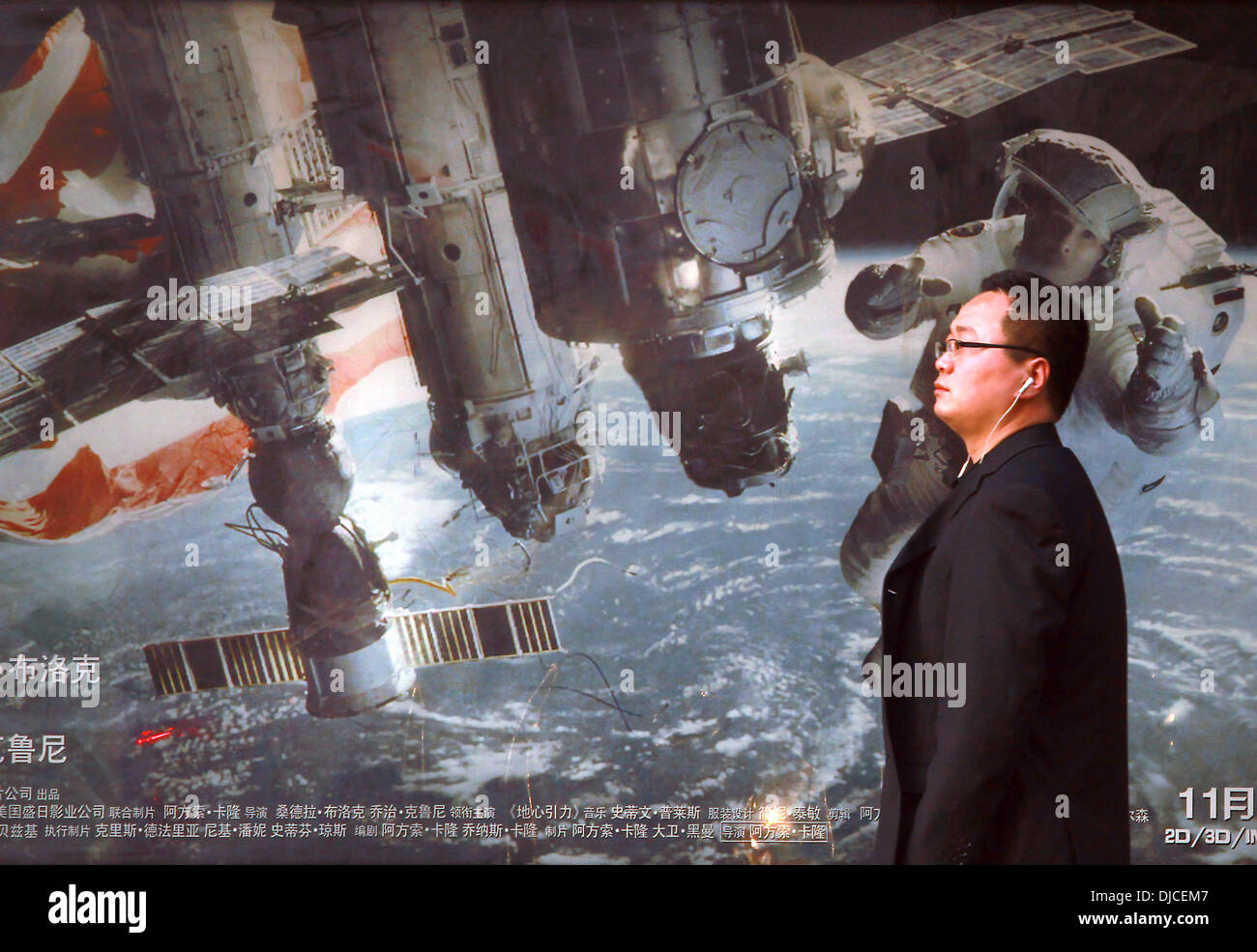 Nov. 24, 2013 - un uomo cinese attende un autobus di fronte un marciapiede pubblicità per un filmato di circa astronauti americani e la stazione spaziale internazionale a Pechino il 24 novembre 2013. La Cina ha la possibilità nel prossimo decennio per superare gli Stati Uniti nello spazio programmi, costringendo il governo degli Stati Uniti per intensificare il finanziamento della NASA per mantenere la sua posizione di leadership, entrare in partnership con il Cinese o rischiare di cadere dietro la politica spaziale dicono gli esperti. (Credito Immagine: © Stephen rasoio/ZUMAPRESS.com) Foto Stock