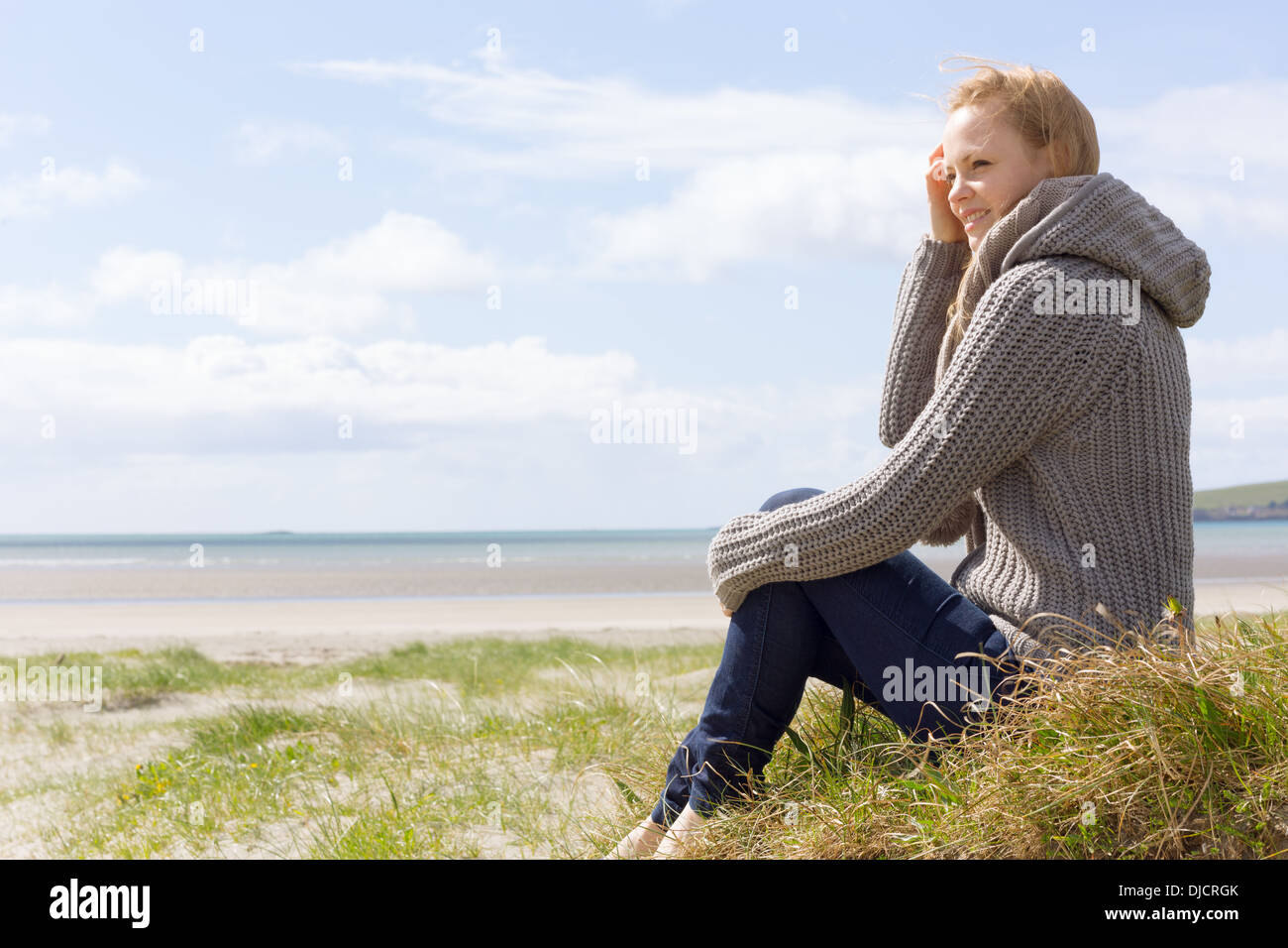 Attraente donna seduta sulla spiaggia Foto Stock