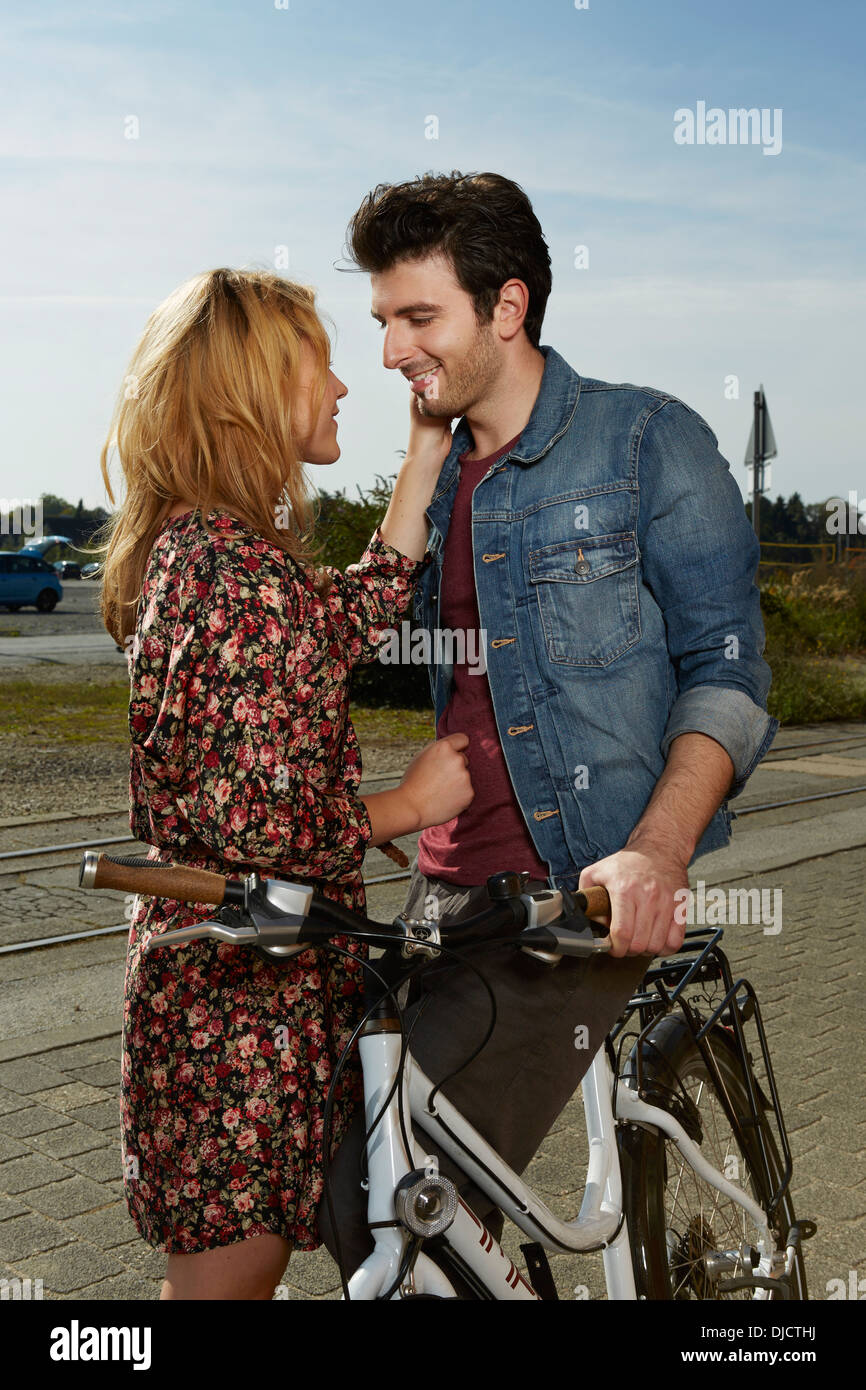 Germania, Dusseldorf, giovane donna che accarezzano l'uomo, tenendo bicicletta Foto Stock