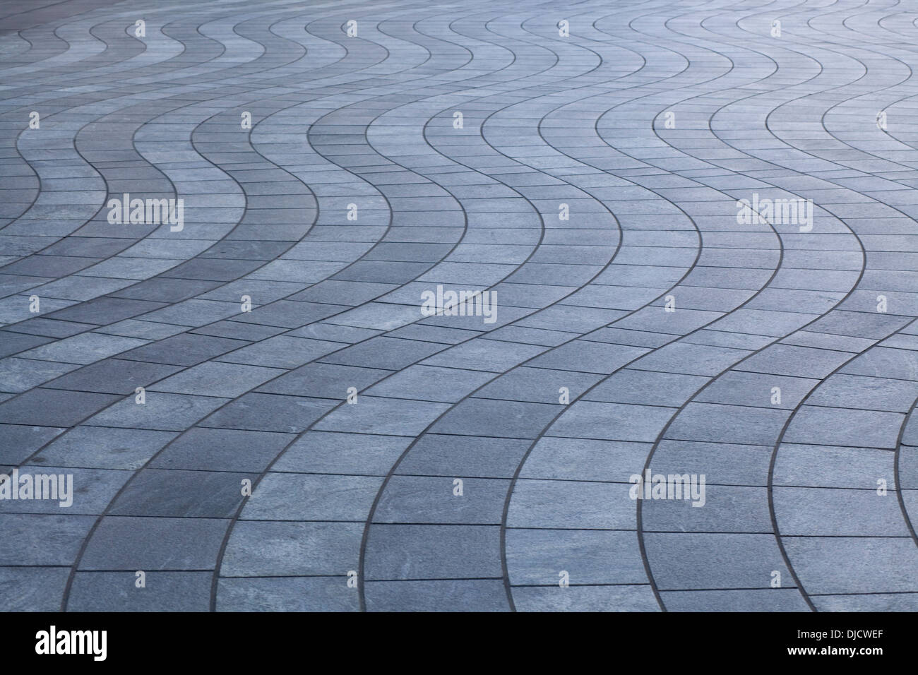 Grigio e bianco strisce ondulate di curva square pavimentazione in pietra Foto Stock