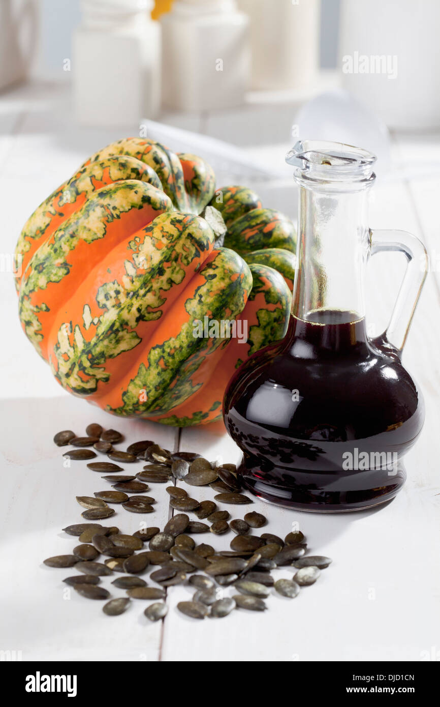 Multicolore di squash (Cucurbita maxima), semi di zucca e la caraffa con olio di semi di zucca studio shot Foto Stock