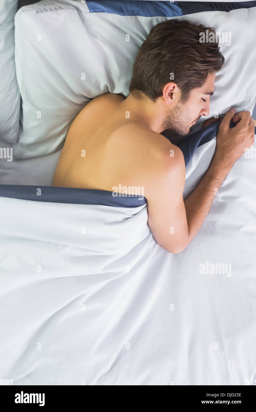 Dai capelli scuri giovane uomo dorme nel suo letto Foto Stock