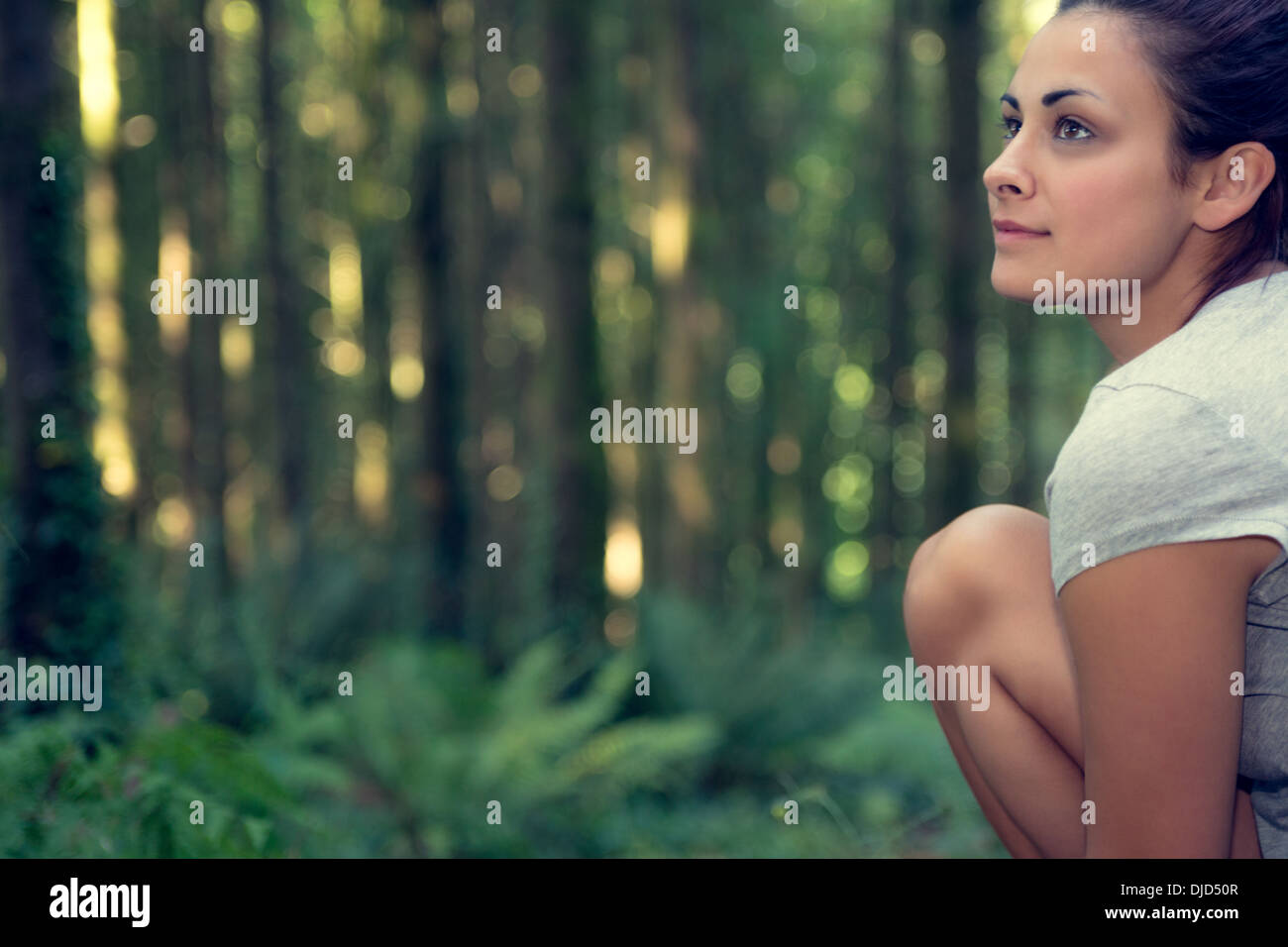 Attraente brunette donna seduta in una foresta Foto Stock