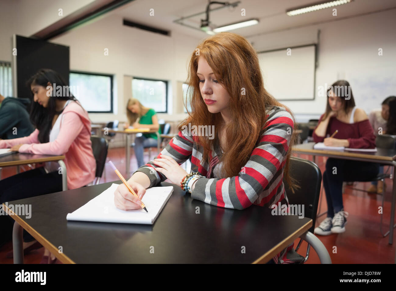 Focalizzato studentessa prendere appunti in classe Foto Stock