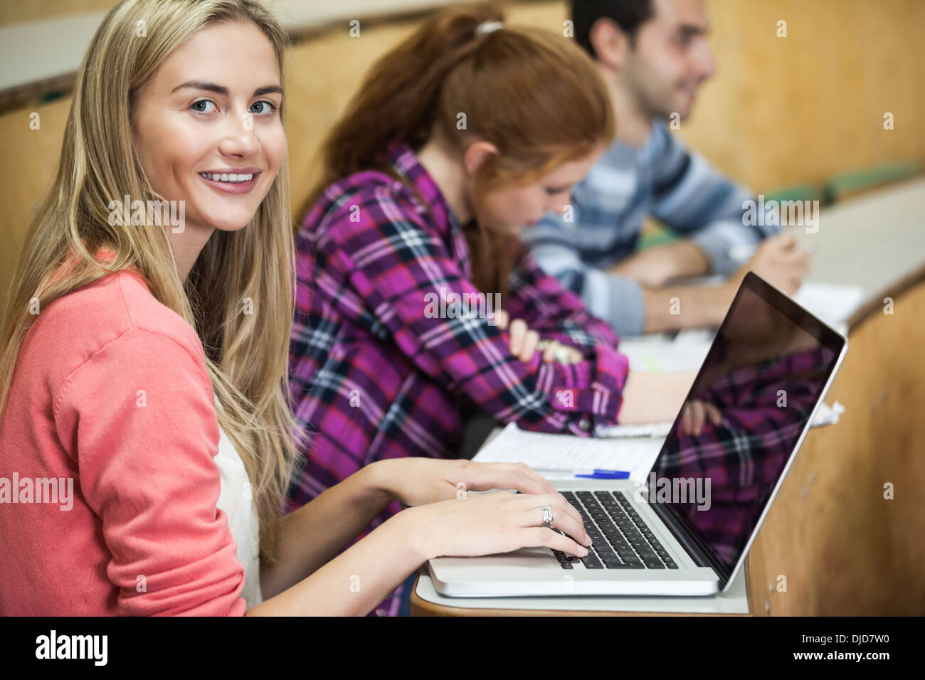 Felice studente seduto in una conferenza utilizzando il suo laptop Foto Stock