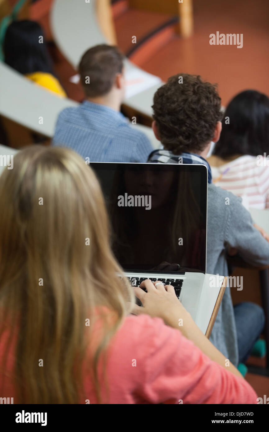 Bionda studente seduto in una conferenza utilizzando il suo laptop Foto Stock