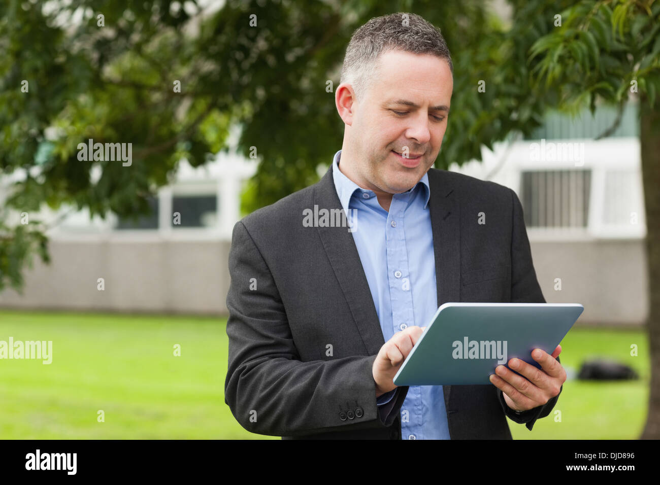 Allegro docente utilizzando il suo tablet al di fuori del campus Foto Stock