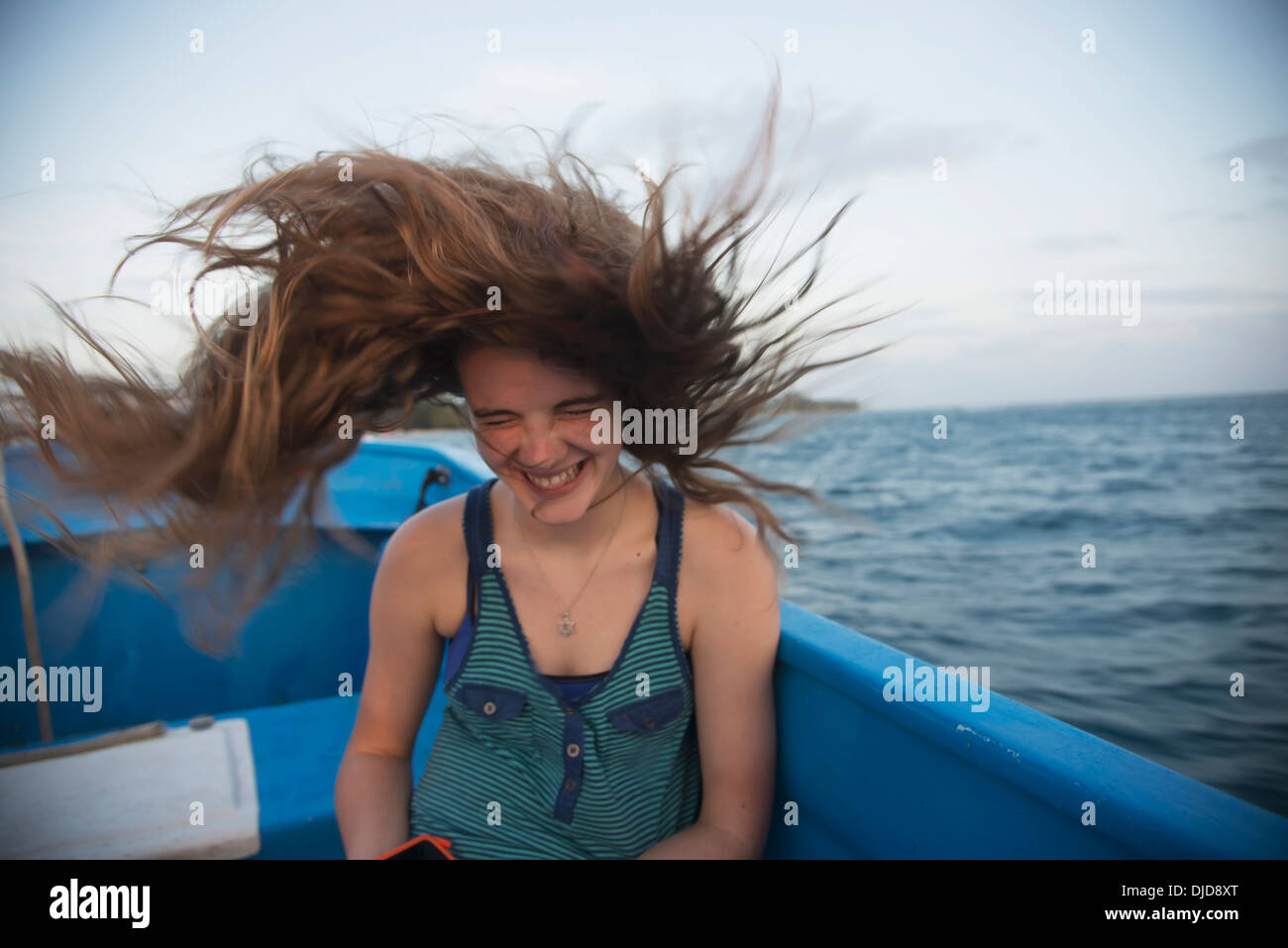 Una Ragazza capelli lunghi fustigazione attraverso l'aria su un giro in barca; Utila, isole di Bay, Honduras Foto Stock