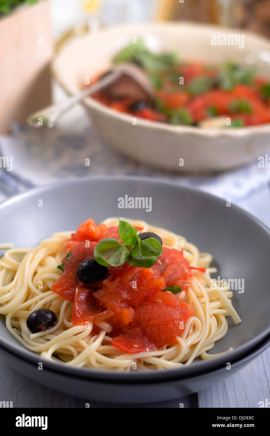 Spaghetti con sugo di pomodoro grigliate con olive nere e foglie di basilico, studio shot Foto Stock