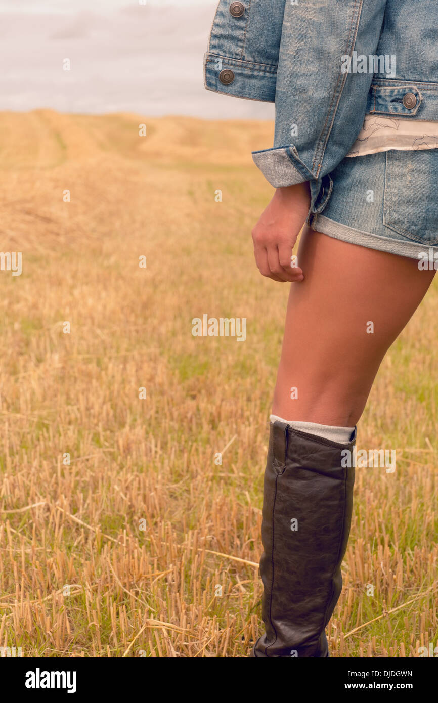 La sezione centrale della donna in denim shorts e stivali al campo di cereali Foto Stock