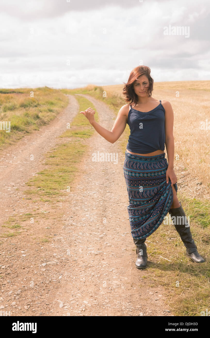 Donna autostop su sterrato strada di campagna Foto Stock