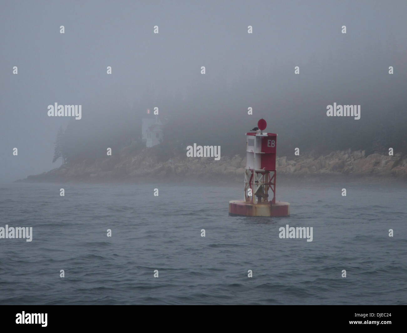 Un rosso e bianco boa e il porto basso faro nella nebbia lungo la costa del Maine USA Foto Stock