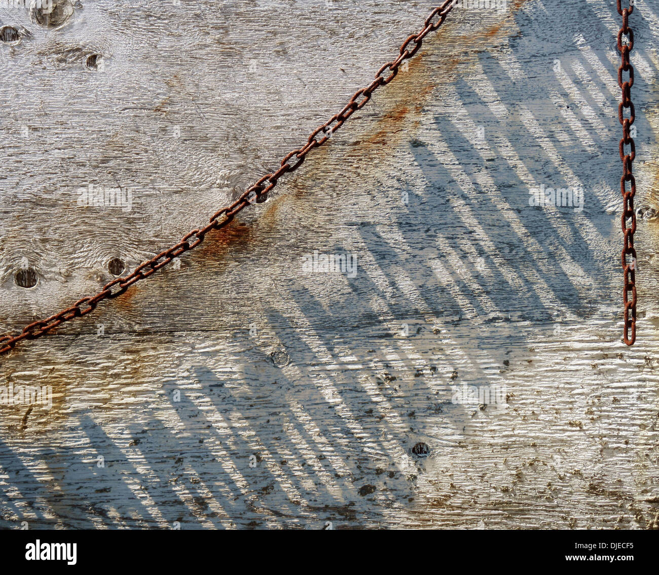 Un arco arrugginito della catena foglie lunghe ombre su un vecchio muro dipinto grazie all'angolo del mezzogiorno momento sun scrematura attraverso di esso. Foto Stock