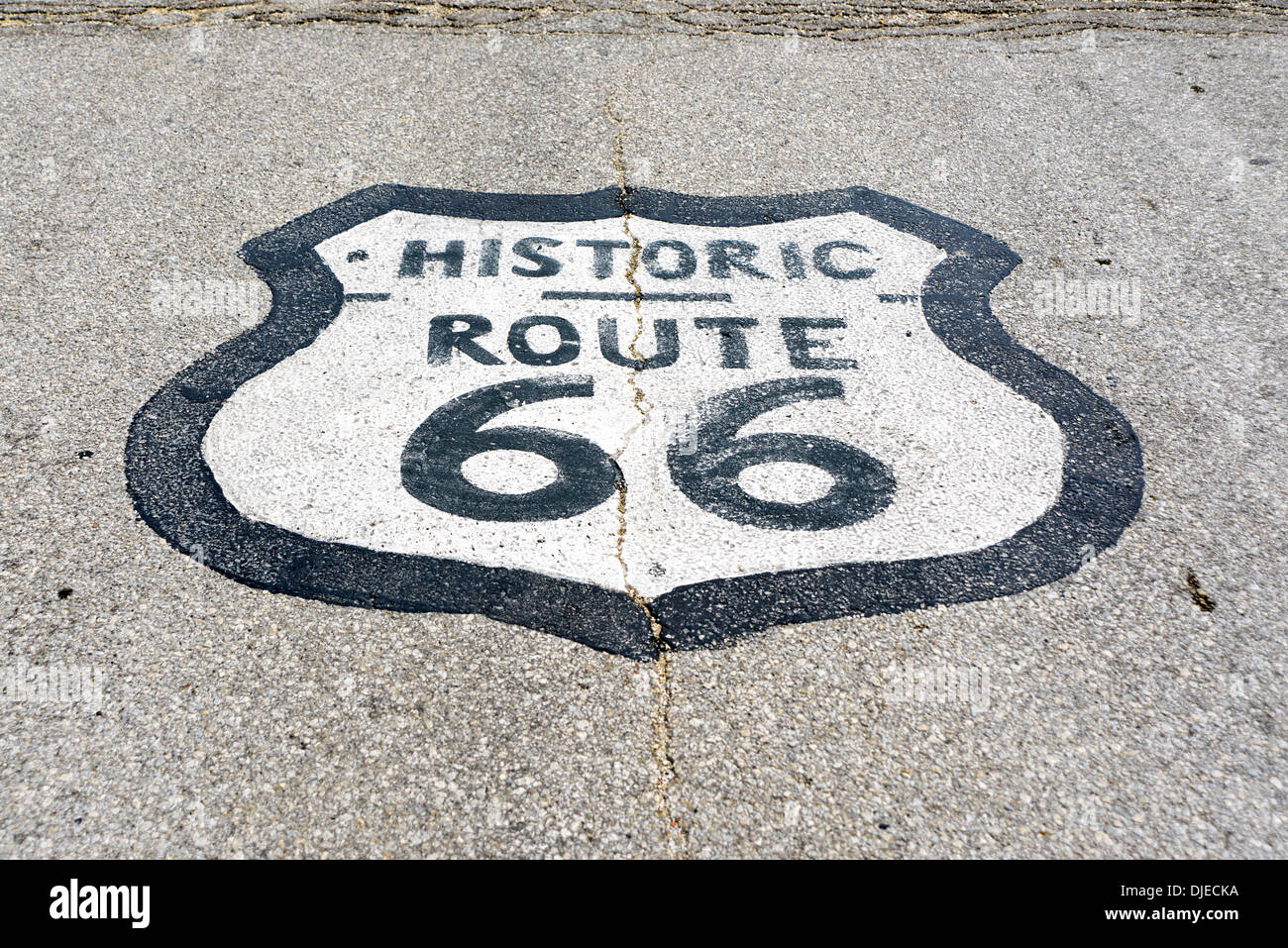 Sun-cotta foto della storica Route 66 cartello stradale dipinta su una strada asfaltata sul tratto di percorso 66 tra Chicago, Illinois e San Louis, Missouri Foto Stock