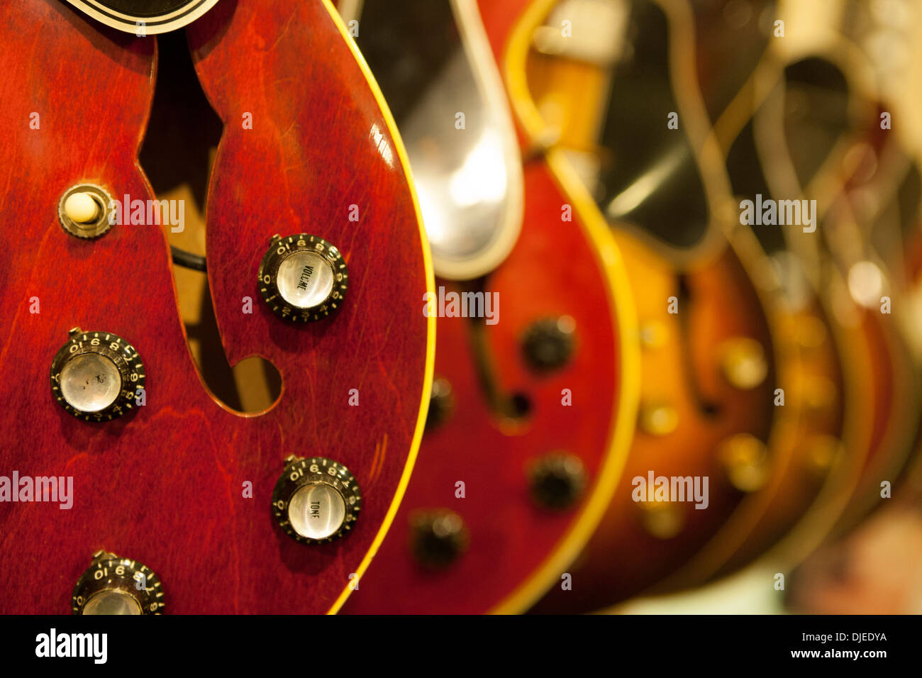 Una chiusura di un rosso chitarra elettrica e i suoi vari controlli audio come ad esempio il volume. Sembra di essere utilizzato e per la vendita in un negozio Foto Stock