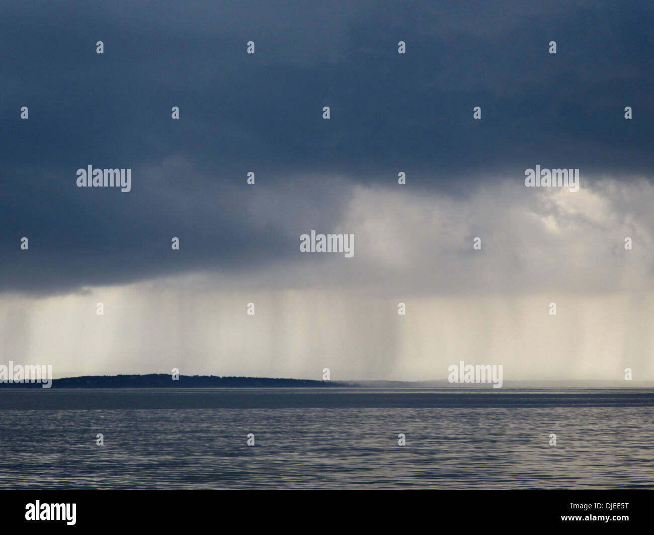 Visibile pioggia che cade dalle nuvole scure sull'oceano. Foto Stock