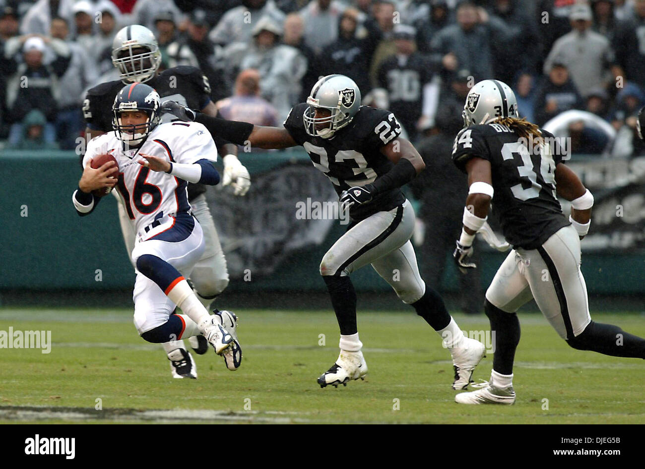Oct 17, 2004; Oakland, CA, Stati Uniti d'America; NFL Football: quarterback Denver Jake Plummer inizia a scorrere dopo una lunga corsa per un primo verso il basso nel terzo trimestre. #23 per i raider Marques Anderson insegue. Foto scattata durante i raider vs Broncos gioco presso la Network Associates Coliseum. Foto Stock