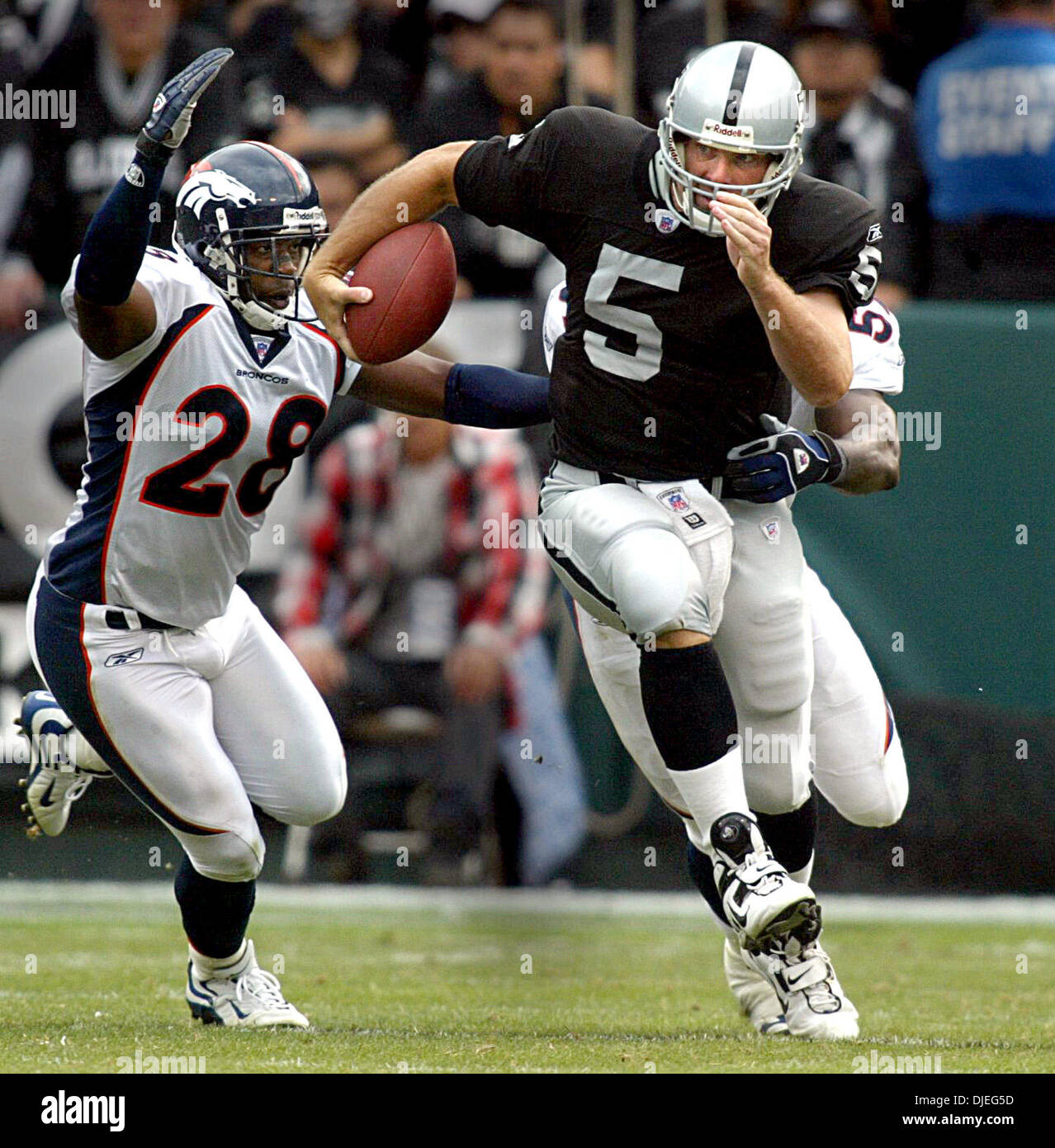 Oct 17, 2004; Oakland, CA, Stati Uniti d'America; NFL Football: Kerry Collins ottenere azionato verso il basso da Bronco tacklers #59 Donnie Spragan e (sinistra) #29 Kenroy Kennedy per un sacco nel secondo trimestre. Foto scattata durante i raider vs Broncos gioco presso la Network Associates Coliseum. Foto Stock