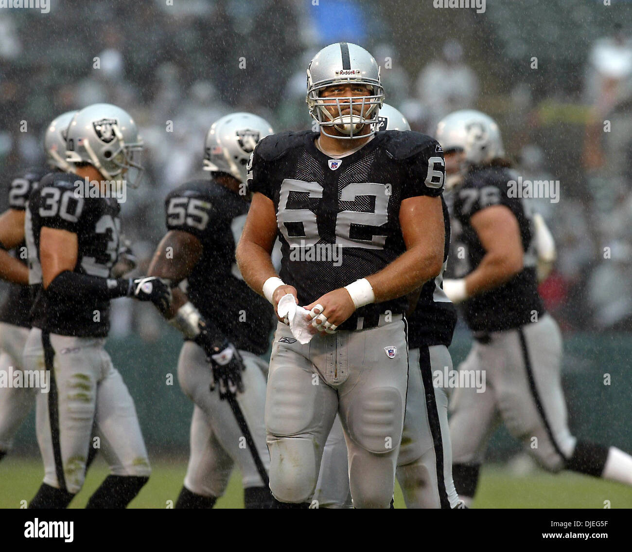 Oct 17, 2004; Oakland, CA, Stati Uniti d'America; NFL Football: tarda nel terzo trimestre come la pioggia arriva giù hard #62 Adam Treu sembra triste come si guarda verso la scheda punteggio. Foto scattata durante i raider vs Broncos gioco presso la Network Associates Coliseum. Foto Stock