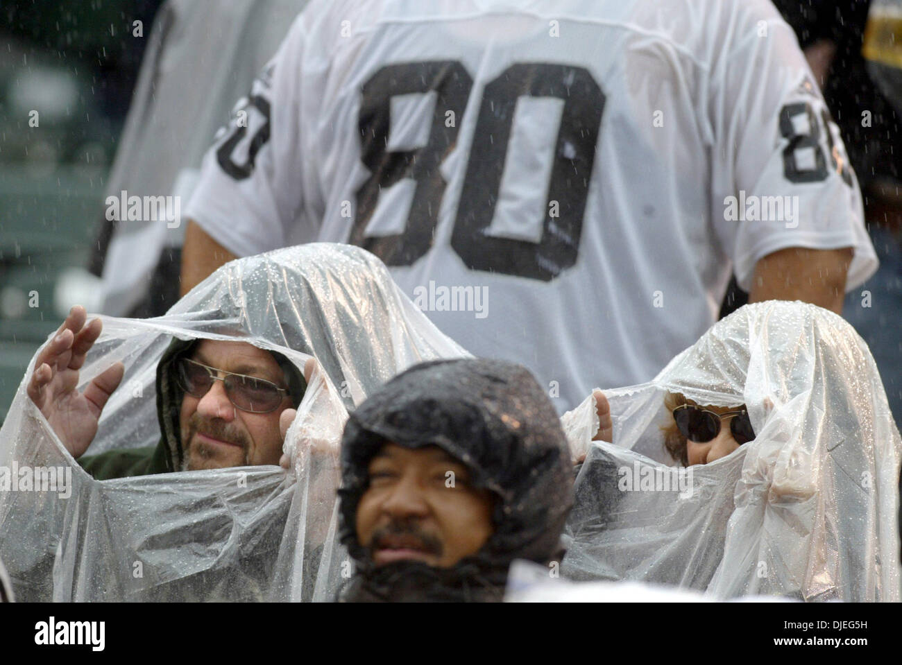 Oct 17, 2004; Oakland, CA, Stati Uniti d'America; NFL Football: Raider fans Edward Eggiman e sua moglie Patty provare e conservare in un luogo asciutto durante un Raider. Foto scattata durante i raider vs Broncos gioco presso la Network Associates Coliseum. Foto Stock