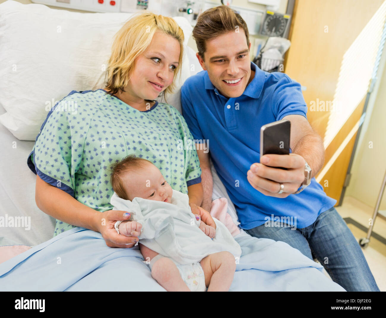 L'uomo con la donna e Babygirl tenendo Selfportrait attraverso Mobile P Foto Stock
