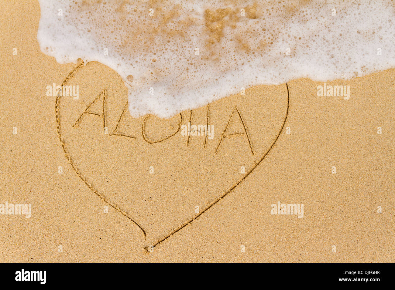 Ocean di acqua di lavaggio su un cuore disegnato nella sabbia con la parola Aloha; Honolulu Oahu, Hawaii, Stati Uniti d'America Foto Stock