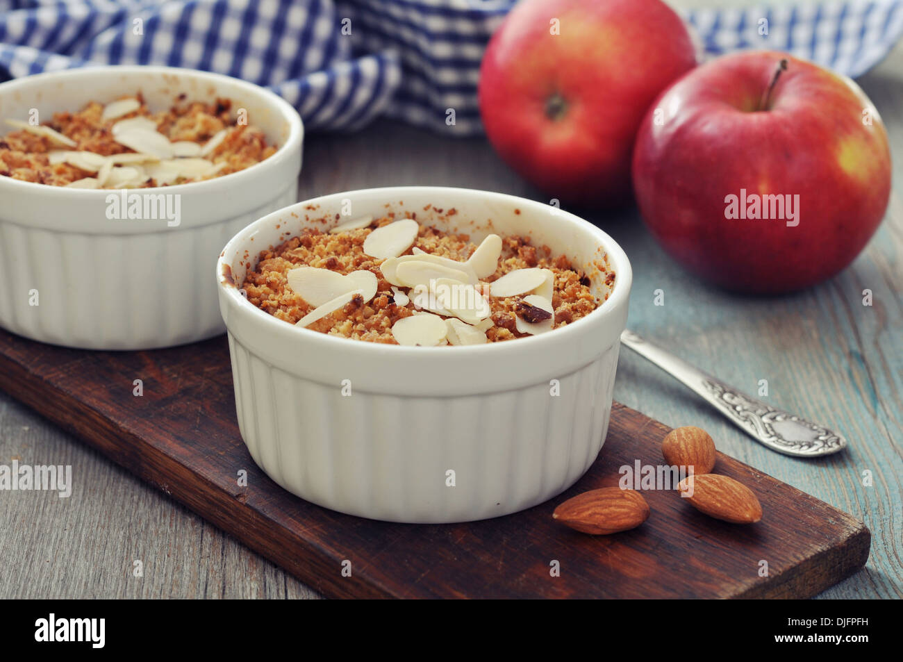 Apple Crumble in stampi ceramici con mele fresche su sfondo di legno Foto Stock