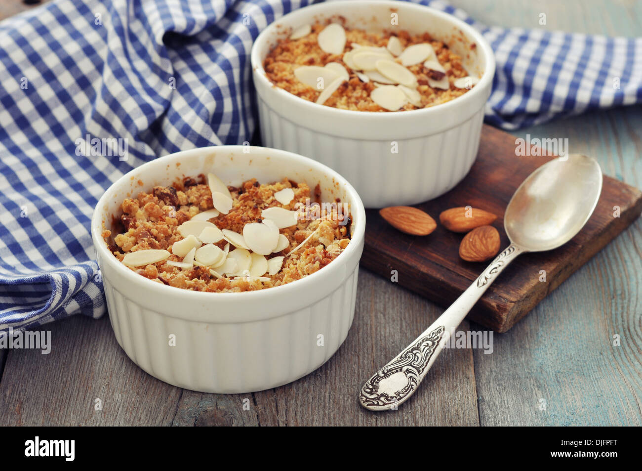 Apple Crumble in stampi ceramici con mele fresche su sfondo di legno Foto Stock