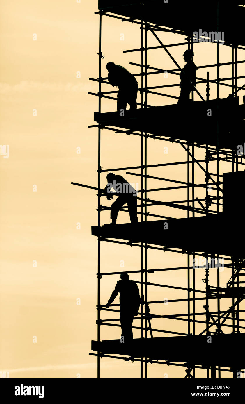 Scaffolders lavorando sul blocco di appartamenti stagliano contro luminoso cielo autunnale Foto Stock