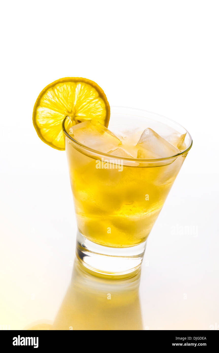 Un fresco e gustoso cocktail con alcool e limone su un tavolo di vetro con riflessione giallo Foto Stock