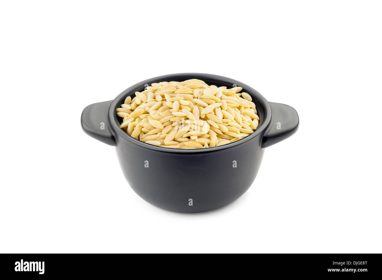 La pasta 'orzo' tipo in un po' di nero piatto in ceramica, buona per la minestra e il minestrone Foto Stock