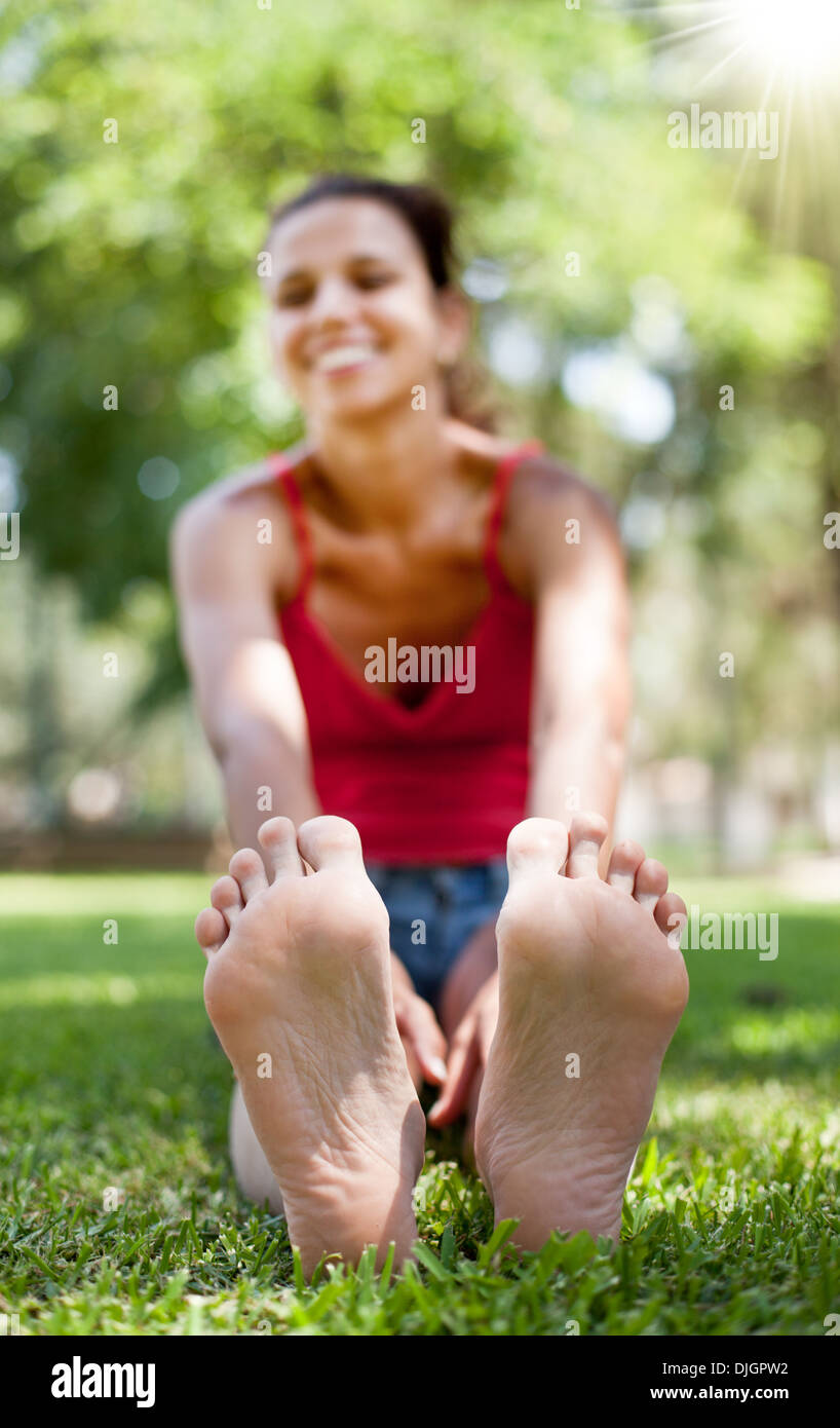 Sorridente giovane donna siede sull'erba. La faccia in defocalizzazione. Foto Stock