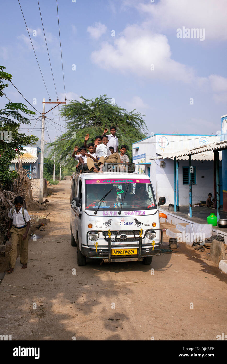 Indian School boys sulla parte superiore di un taxi servizio di mini bus essendo presi a scuola. Andhra Pradesh, India Foto Stock