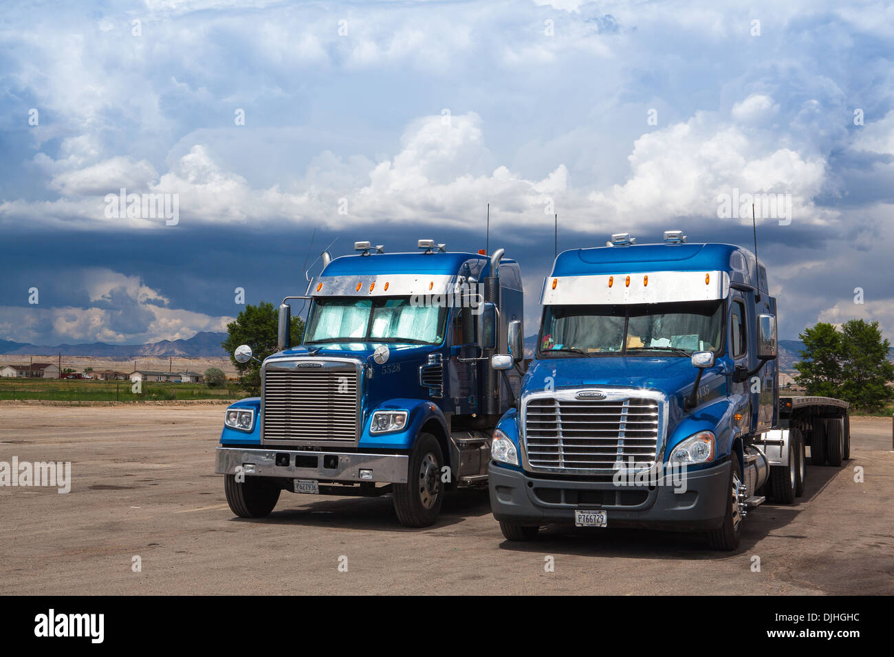 Due tipici american blue Freightliner autocarri su un posto di parcheggio prima di tempesta pesanti in Utah Foto Stock