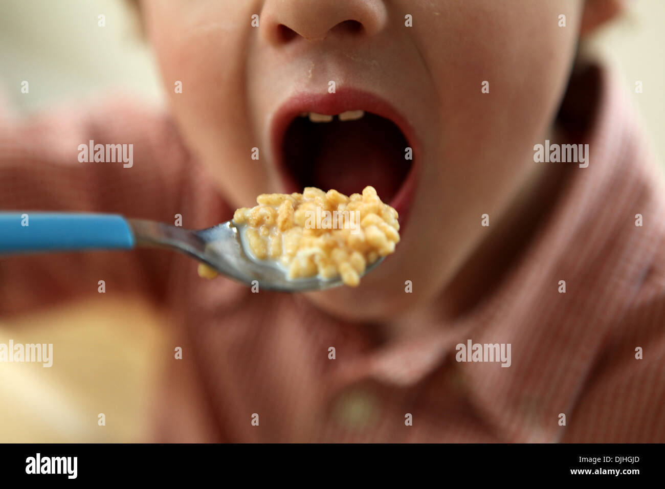 Close-up del bambino la bocca e il cucchiaio con cereali per la prima colazione Foto Stock