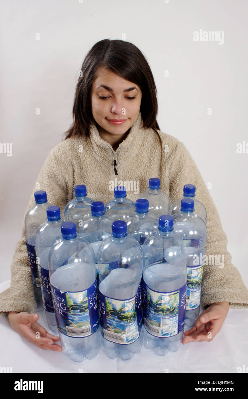 Ragazza adolescente in giacca di lana azienda dodici grandi bottiglie di plastica Foto Stock