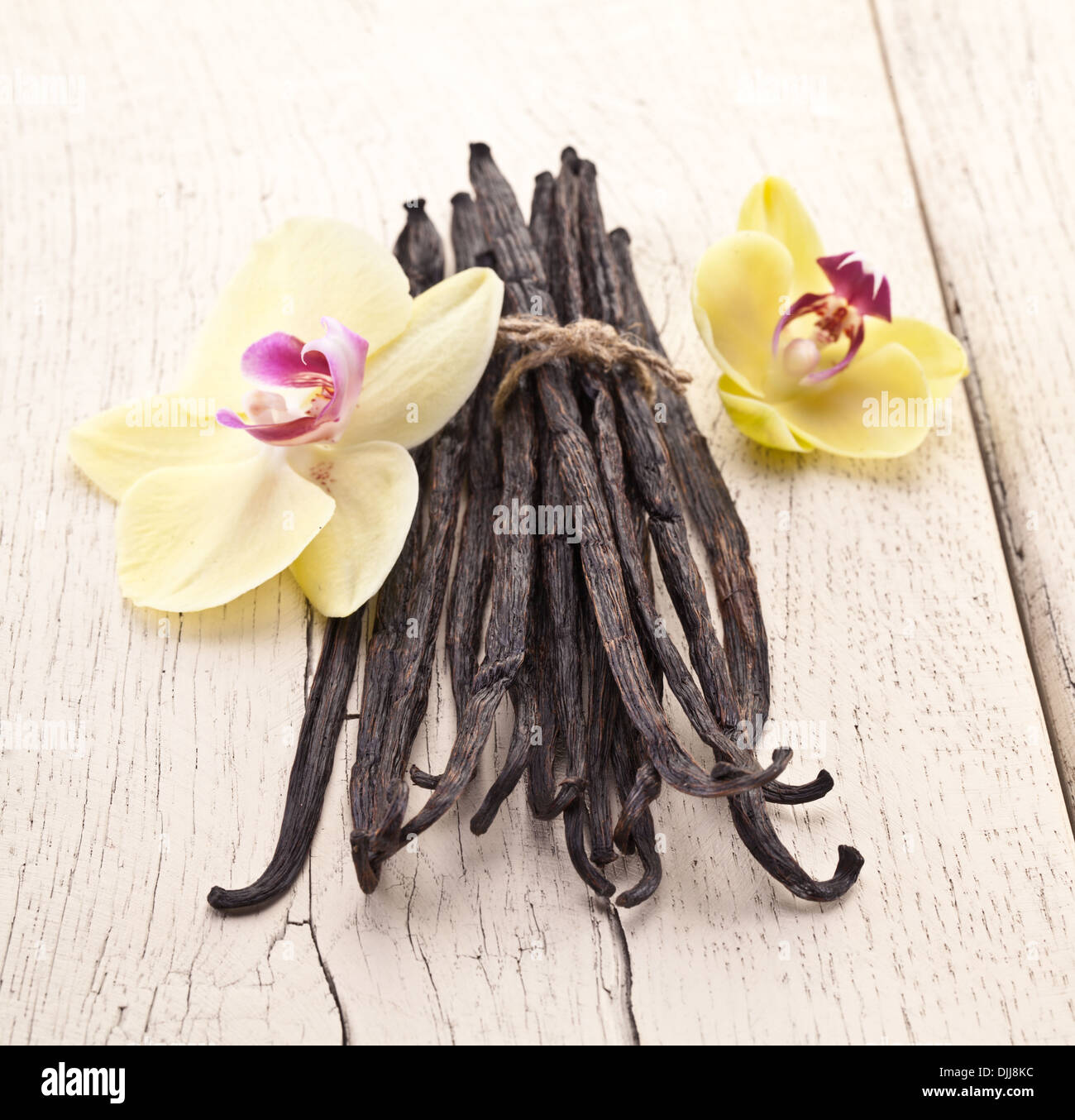 Bastoncini di vaniglia con un fiore di un bianco tavolo di legno. Foto Stock