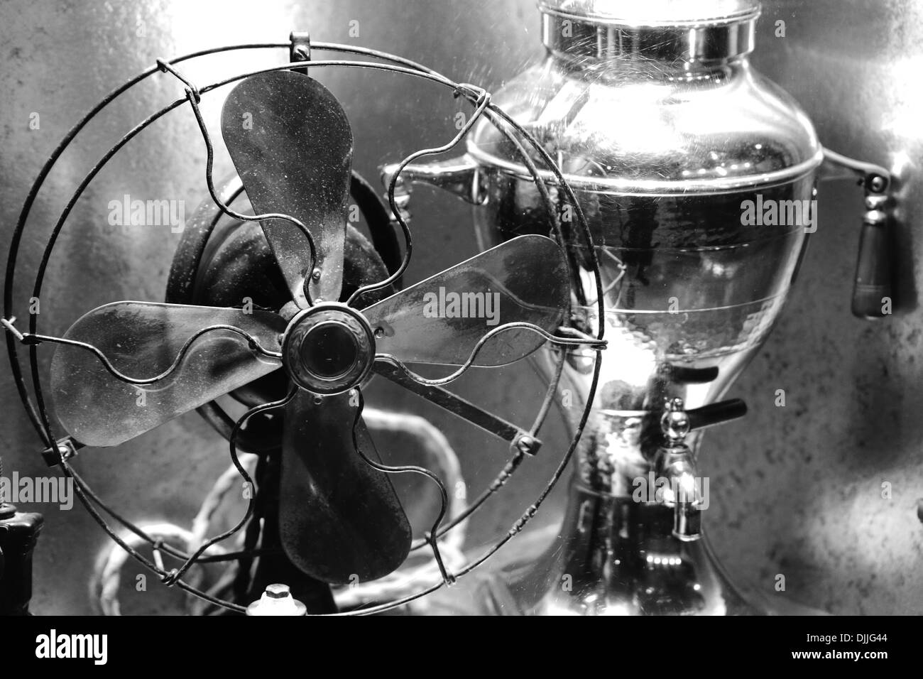Un primo piano di un antico ventilatore elettrico accanto a un tè o un  caffè urna in scala di grigi Foto stock - Alamy