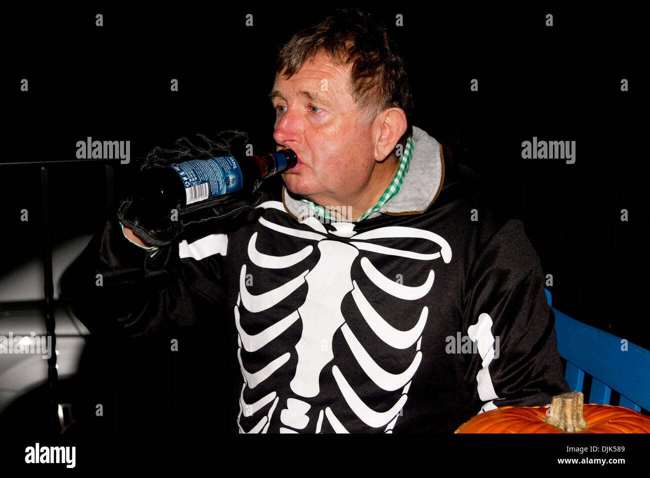 Uomo in Halloween costume scheletro di bere birra da una bottiglia Foto Stock