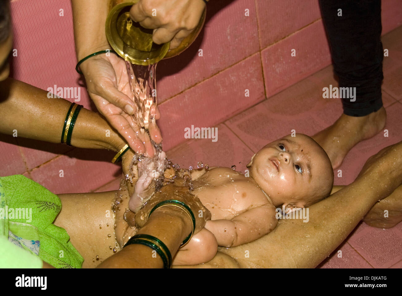 Un bambino indiano godendo di versare l'acqua calda durante il bagno di olio Foto Stock