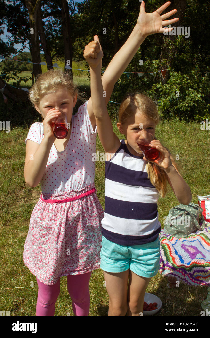 Due ragazze bere squash, in piedi su un picnic in campagna, entrambe le ragazze molto sete nel Somerset, Regno Unito. Foto Stock