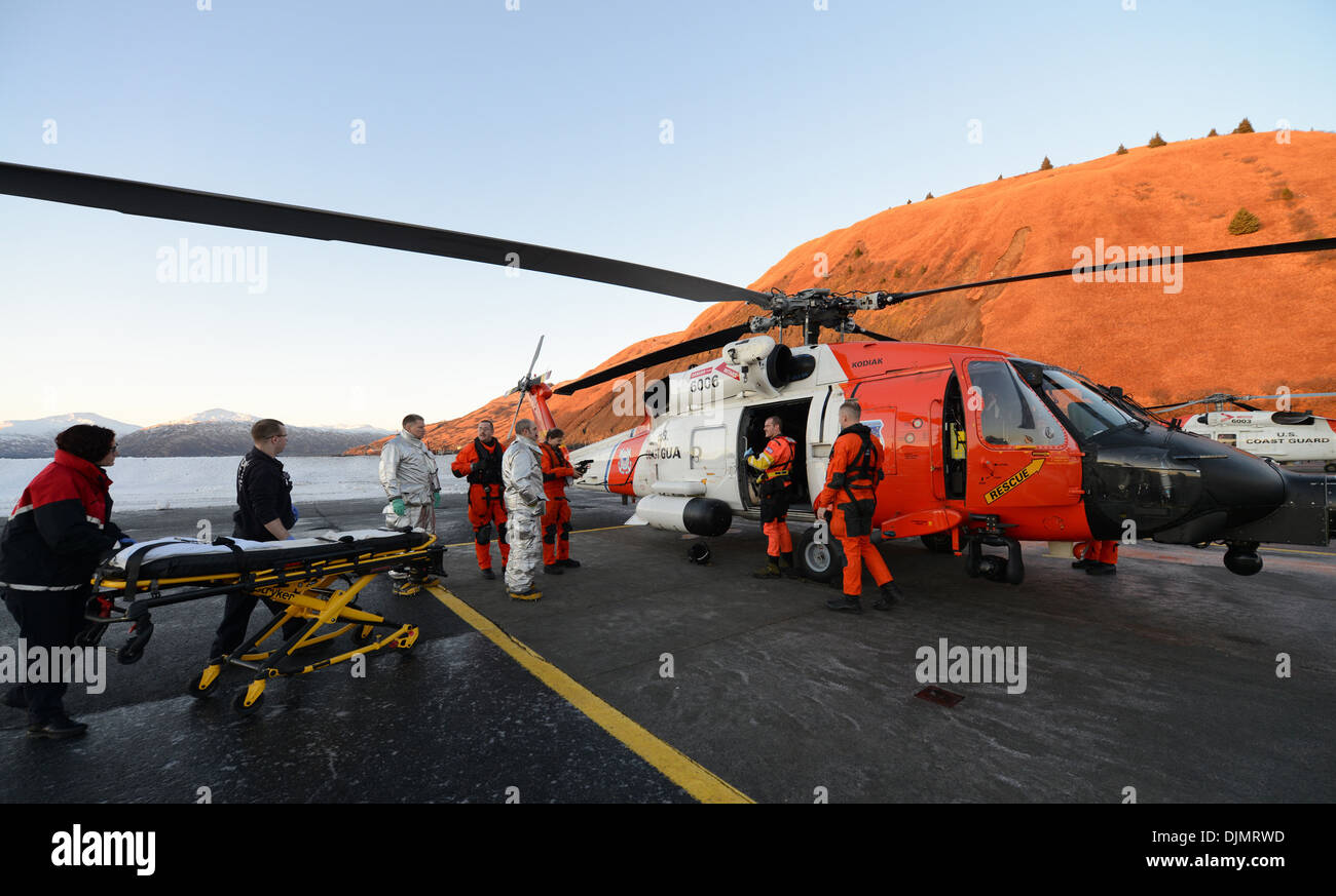 L'equipaggio di un Coast Guard MH-60 elicottero Jayhawk si prepara a trasferire un feriti 56-anno-vecchio uomo filippino per un Kodiak City Fire autoambulanza per ulteriore trasporto per soddisfare un commerciale medevac piano di servizio in Kodiak, Alaska, nov. 27, 2013. Il Jayhawk Foto Stock