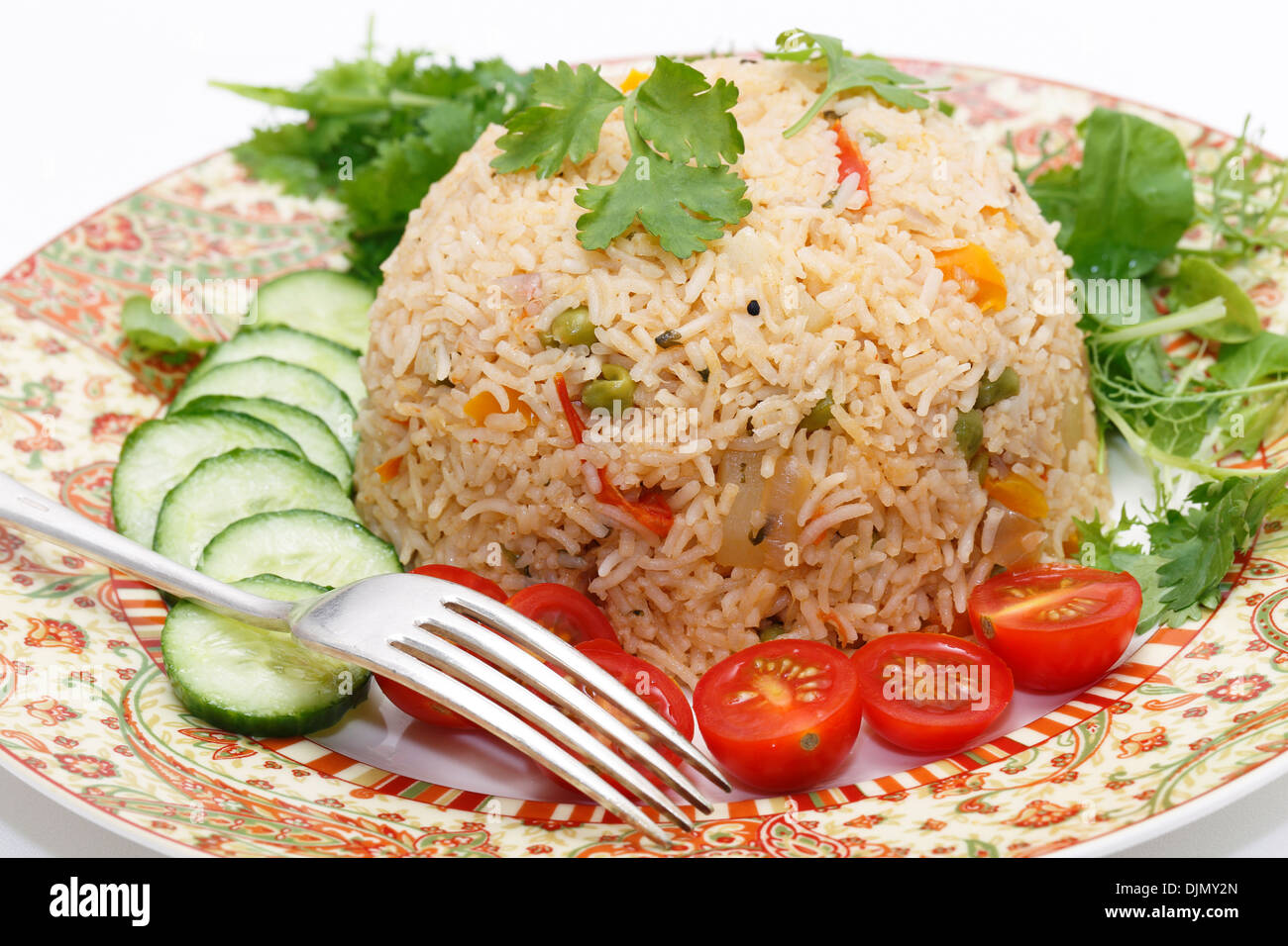 Un sano di pomodoro (thakkali) biriyani con insalata di cetrioli e pomodori ciliegini e alcune foglie fresche, primo piano con una forchetta. Foto Stock