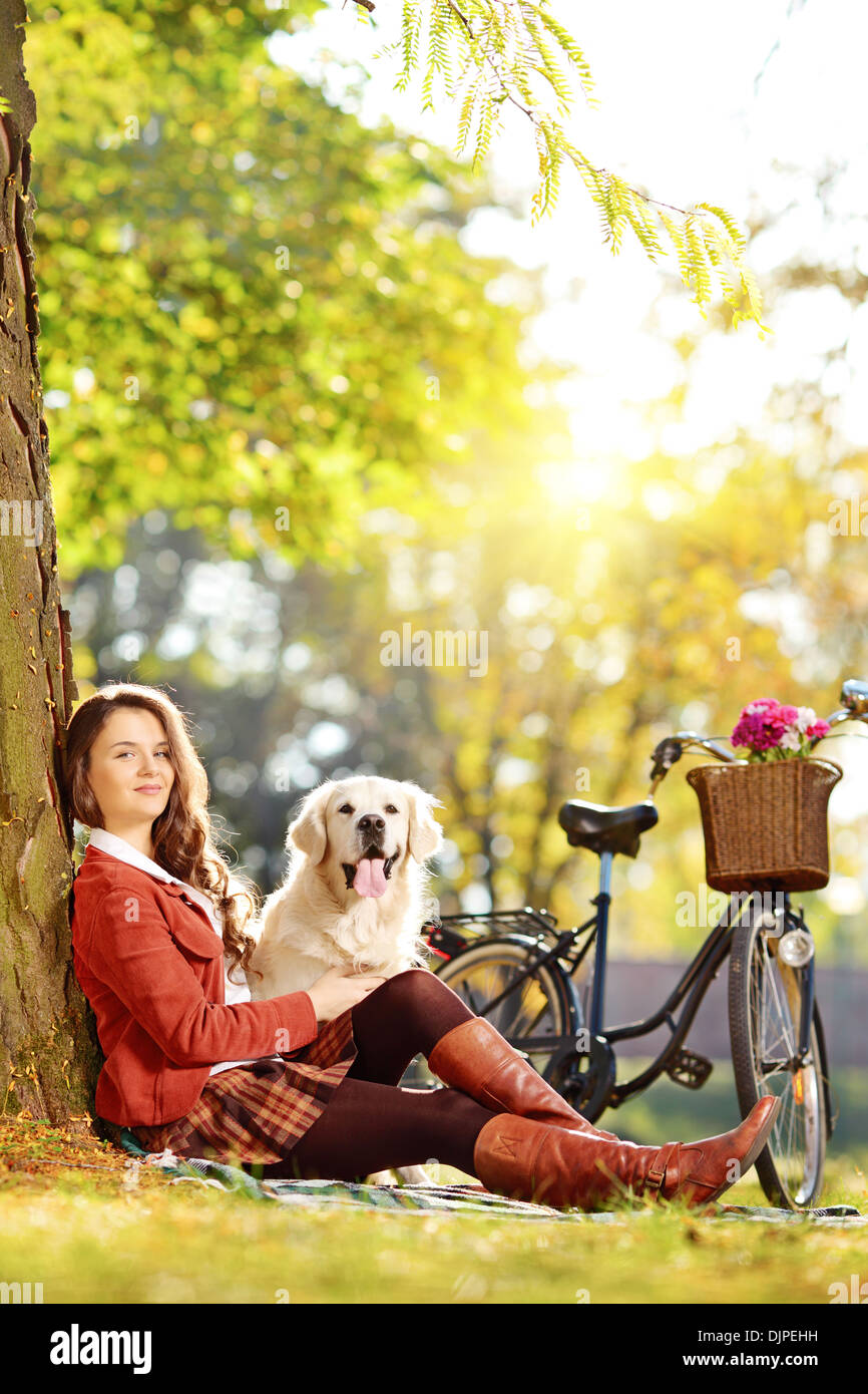 Bella femmina seduto su un prato con il suo labrador retriever cane in un parco Foto Stock